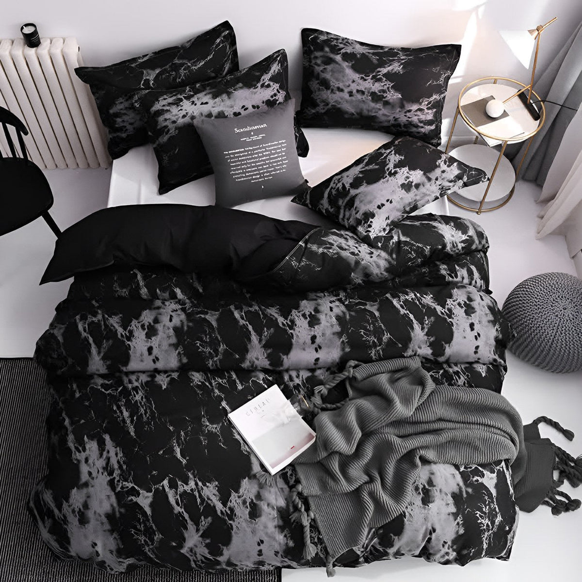 The black marble bedding seen from directly above, made up on a white bed with marble pillowcases, a gray knitted throw and a cushion across one corner.