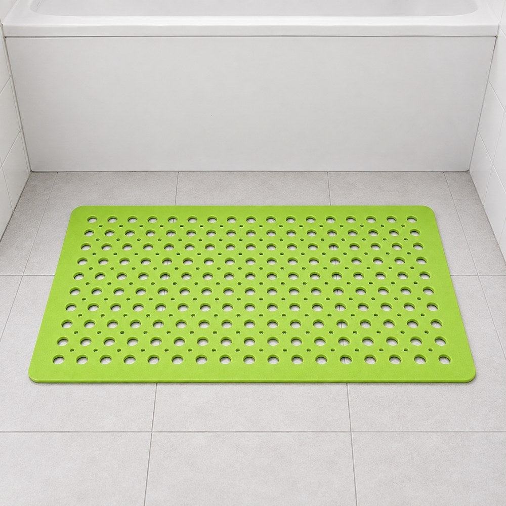 A green shower mat on a white tiled bathroom floor beside a bathtub