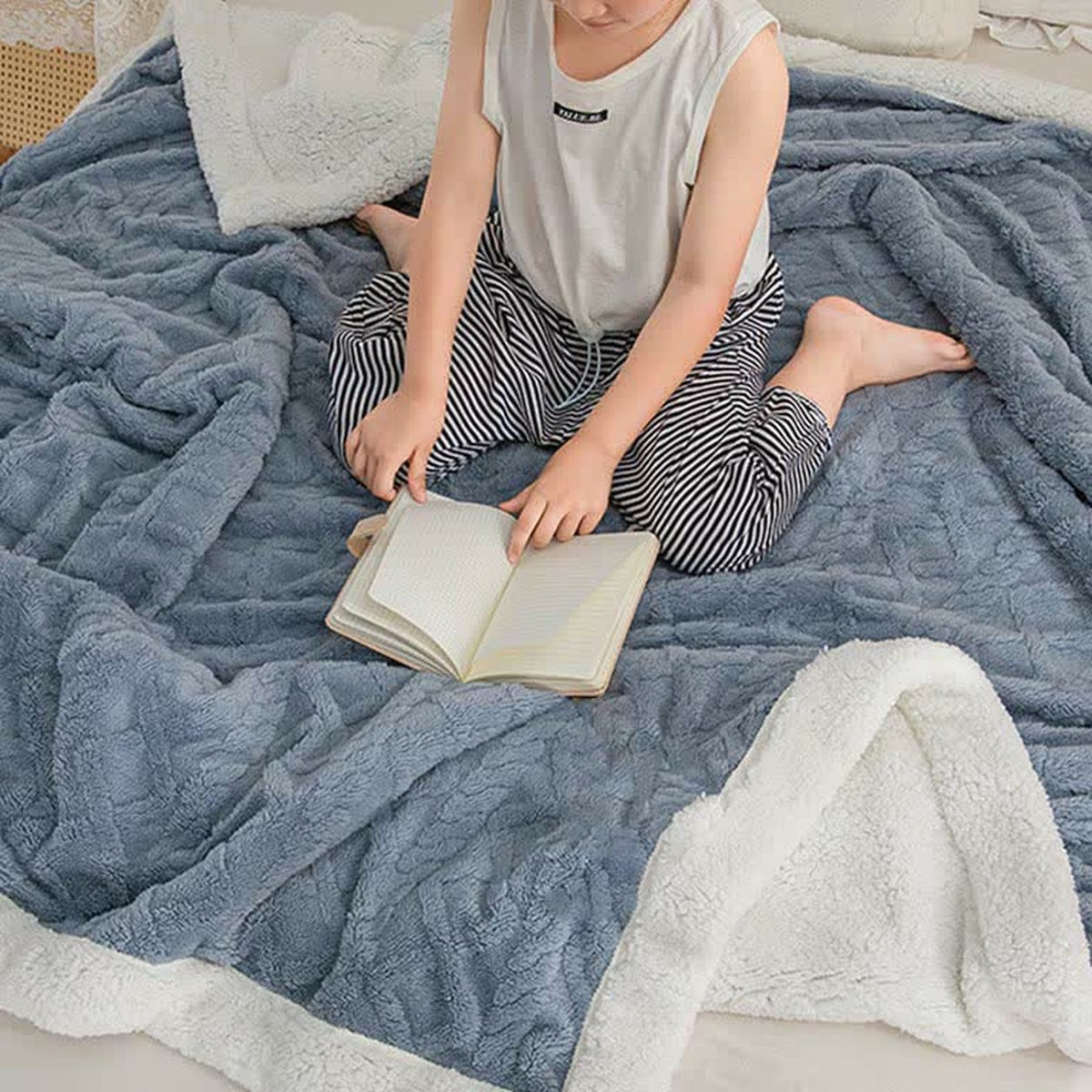 A child wrapped in the blue sherpa throw blanket