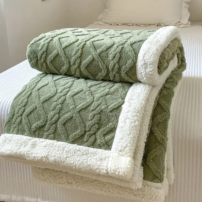 Sage sherpa throw blanket folded on a bed, the raised cable texture facing out and the white sherpa lining showing at the fold