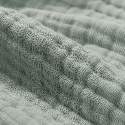 Close-up of the sage cotton muslin, showing the individual threads of the open plain weave, the small square gaps between them and the soft puckering where the six layers are bonded