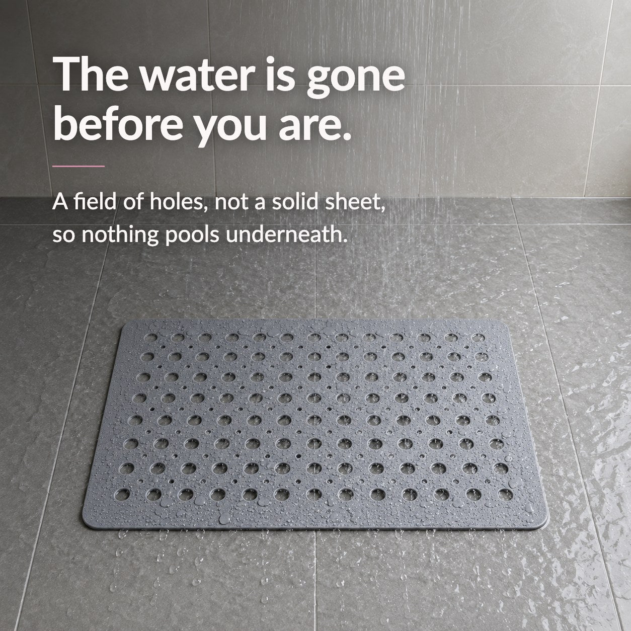 A gray shower mat on a wet tiled shower floor under running water, headed The water is gone before you are