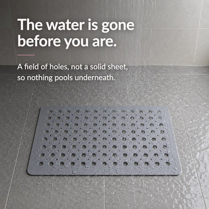 A gray shower mat on a wet tiled shower floor under running water, headed The water is gone before you are