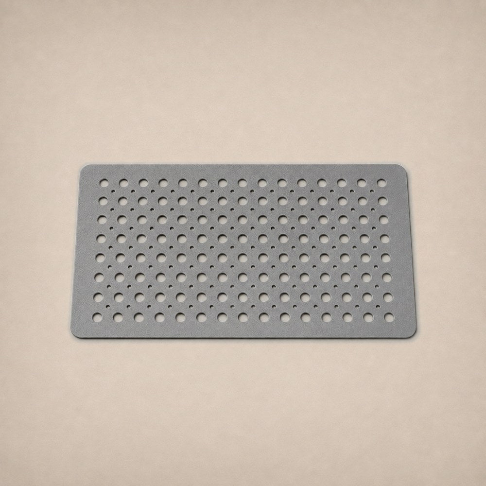 A gray shower mat photographed flat on a warm plaster studio backdrop