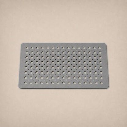 A gray shower mat photographed flat on a warm plaster studio backdrop