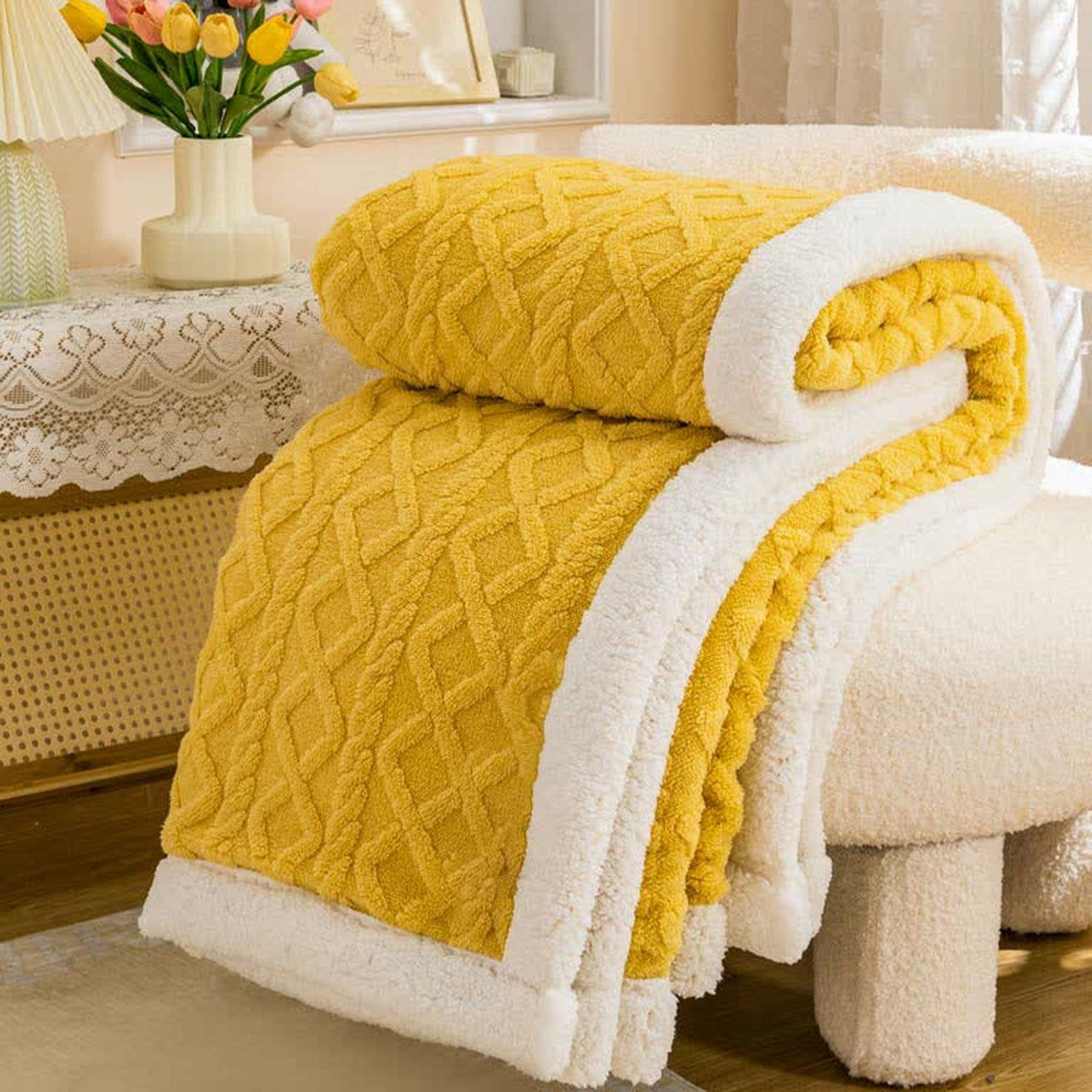 Mustard sherpa throw blanket rolled and folded, the raised cable and diamond texture facing out