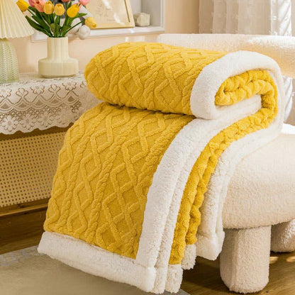 Mustard sherpa throw blanket rolled and folded, the raised cable and diamond texture facing out