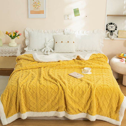 The mustard sherpa throw blanket across the end of a made bed