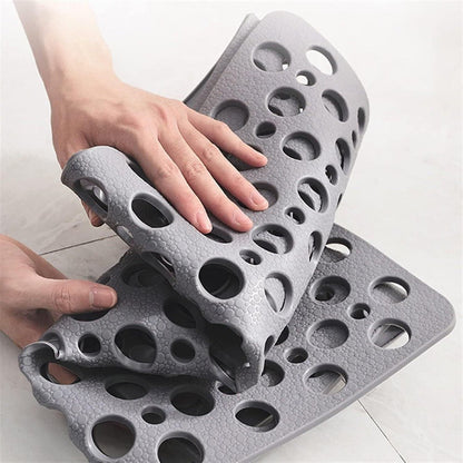 Two hands bending a gray shower mat back on itself to show the suction cups covering its underside