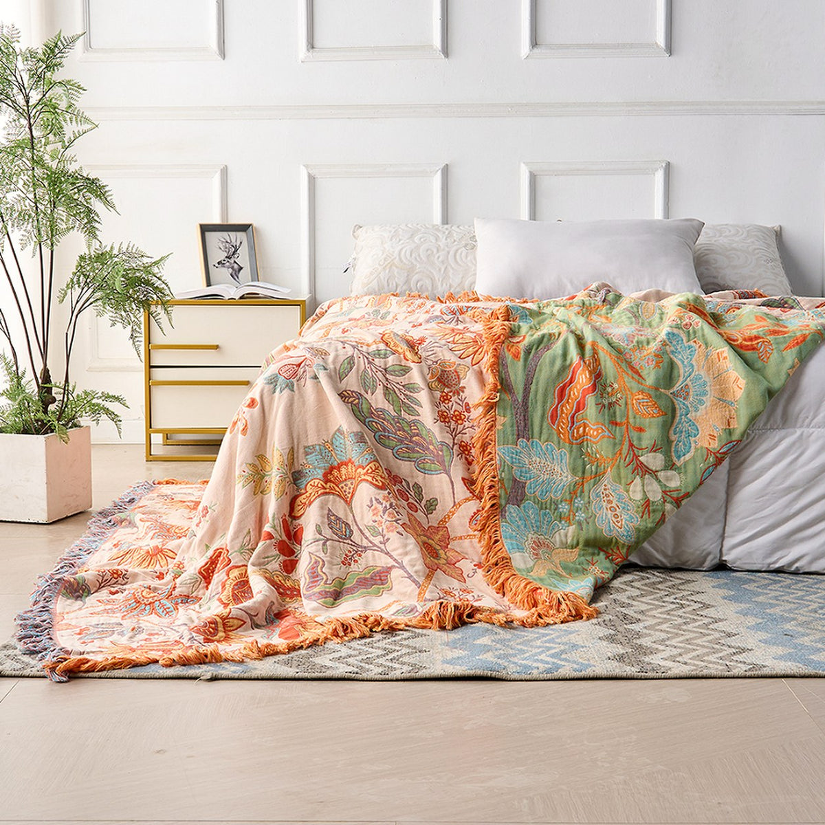 The throw over the corner of a bed with the cream face on one side and the sage green reverse turned back on the other, showing both faces in the same picture.