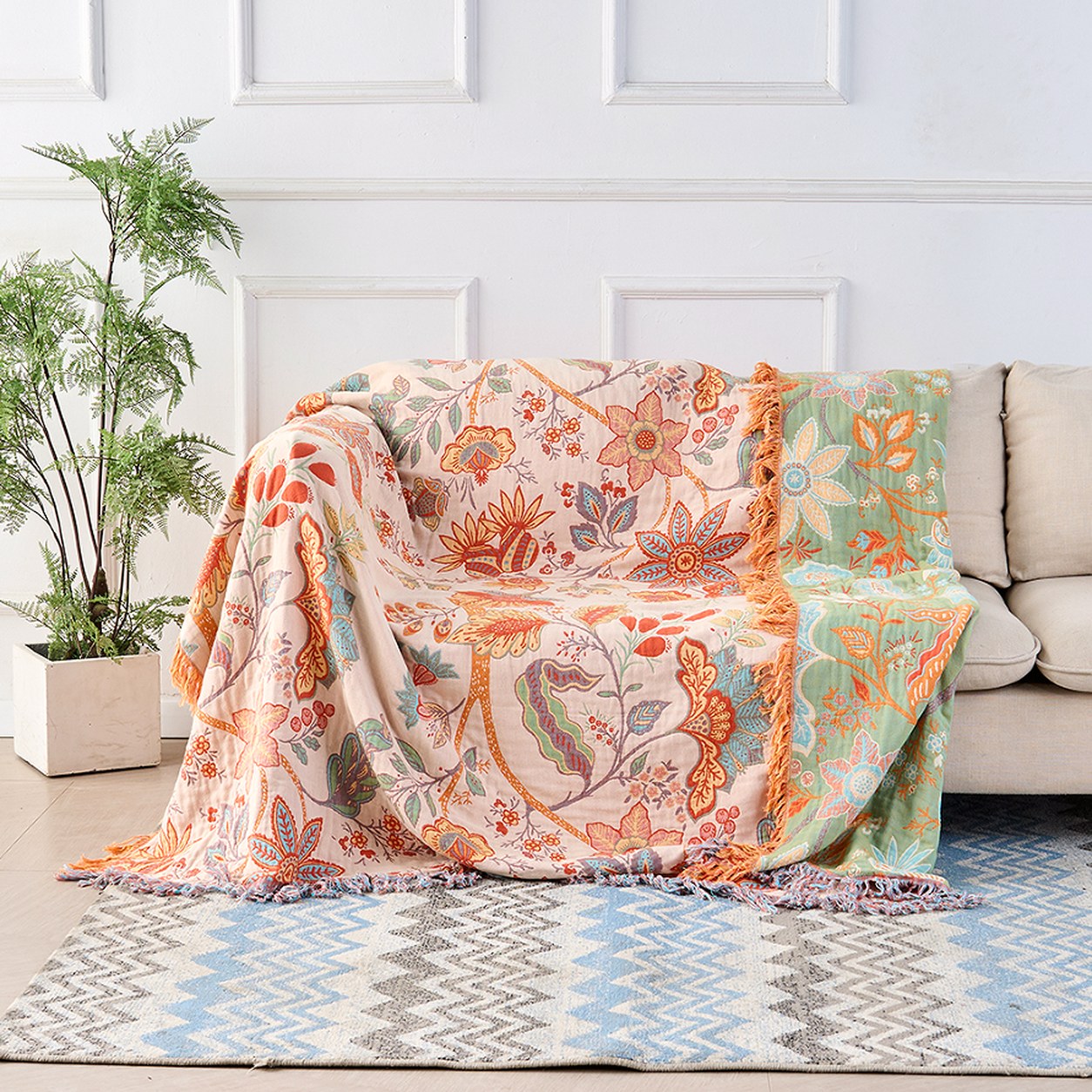 The floral cotton throw opened out across a whole sofa, cream face up, with the sage green reverse showing where it folds over the far arm.