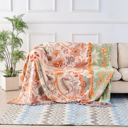 The floral cotton throw opened out across a whole sofa, cream face up, with the sage green reverse showing where it folds over the far arm.