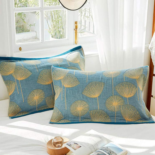 A pair of blue pillow towels on a white bed beside an open book.