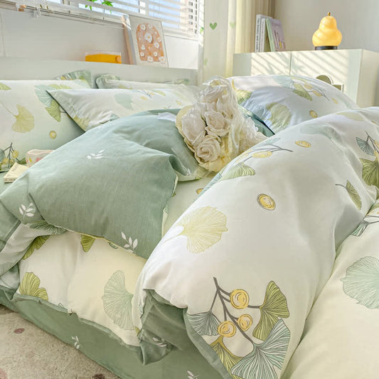 Close on the bed, the ginkgo duvet cover with the sage green side folded back.